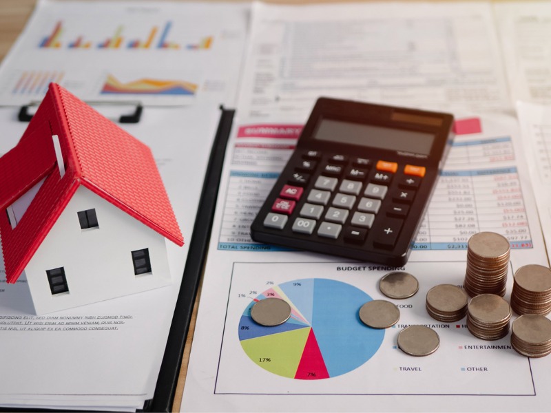 View of calculator, paperwork, house and coins