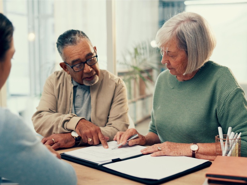 Older couple reviews a contract with a lawyer or financial advisor