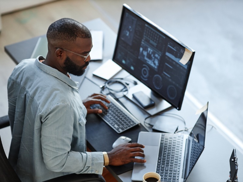 Man looking at two financial screens