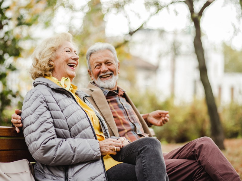 happy senior couple sitting on a bench in the park