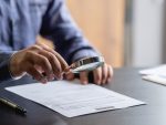 Businessperson examining contract with magnifying glass