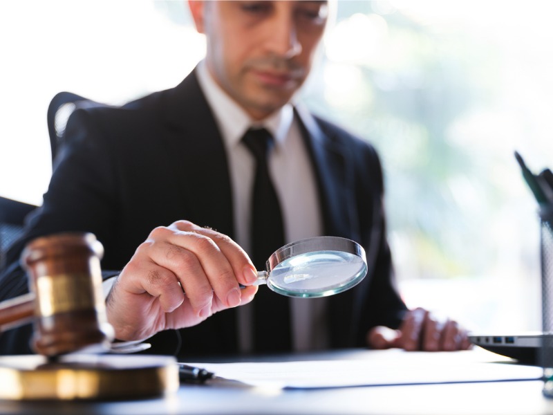 Man reads legal document carefully using magnifying glass