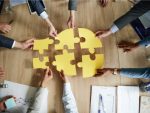 Group of business people holding puzzle pieces at a boardroom table