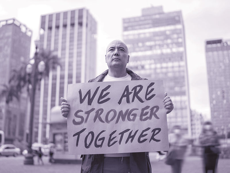 Man holding a sign that says "We are stronger together".