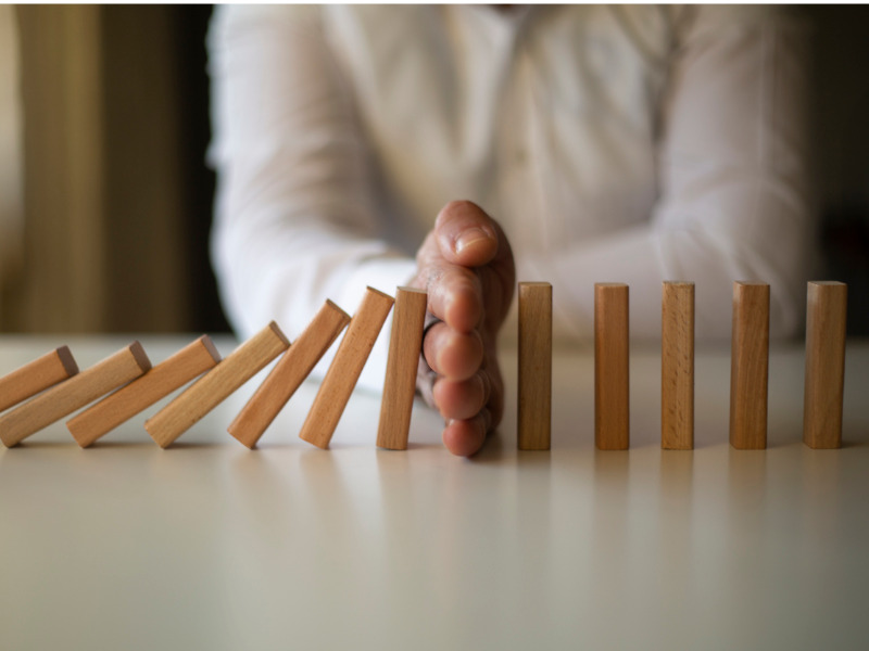 Businessman Stop Domino Effect. Risk Management and Insurance Concept