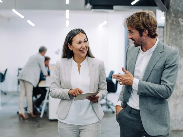 Shot of two coworkers having a discussion in modern office. Businessman and businesswoman in meeting using digital tablet and discussing business strategy.